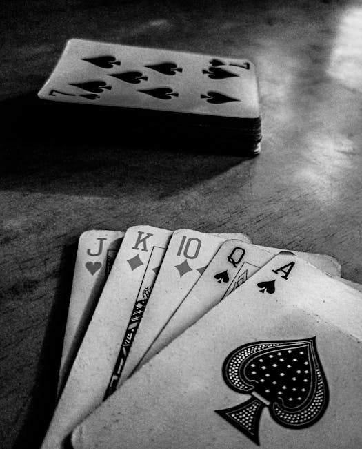 A close-up image of a fan of playing cards laid out on a textured surface, with the Queen of Spades, Ace of Spades, Jack of Hearts, Jack of Clubs, King of Diamonds, and 10 of Spades prominently displa